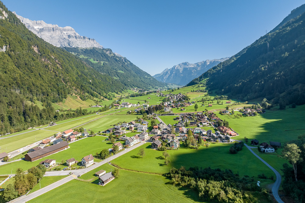 Alpental mit Ortschaft und Bergpanorama