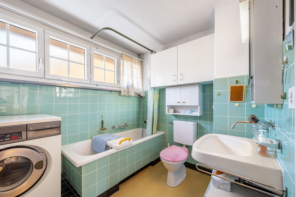 Kleines Badezimmer mit Waschmaschine und Badewanne