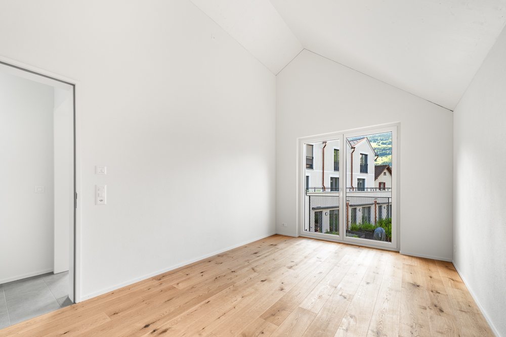 Heller leerer Raum mit Holzboden und großem Fenster