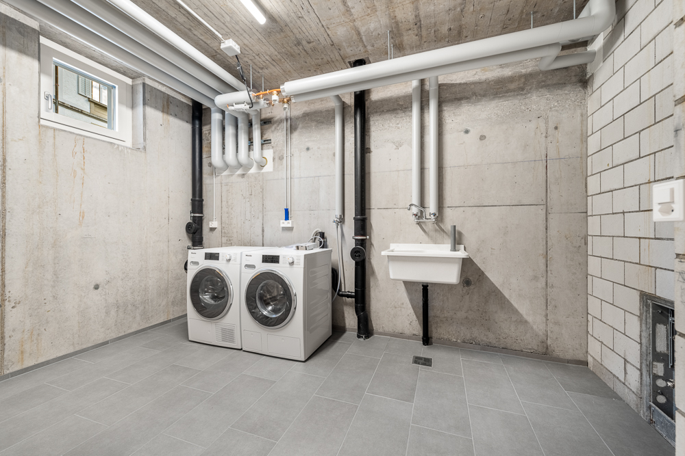 Technik- und Hauswirtschaftsraum mit Waschmaschine, Trockner und Waschbecken