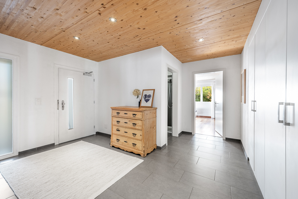 Heller Eingangsbereich mit Holzdecke und grauem Boden