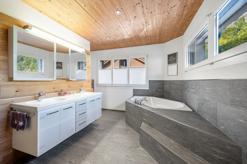Helles Badezimmer mit Holzdecke und grauer Steinverkleidung
