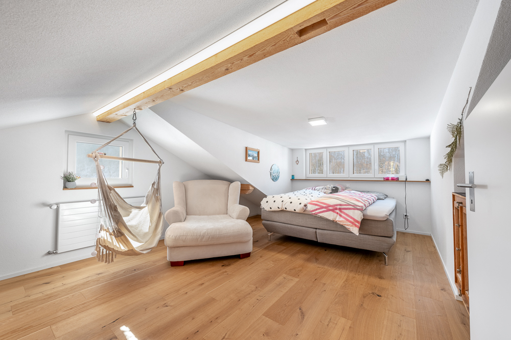 Dachzimmer mit Bett und Hängesessel