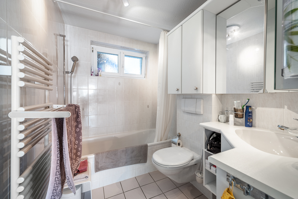 Kleines helles Badezimmer mit Badewanne und Waschtisch