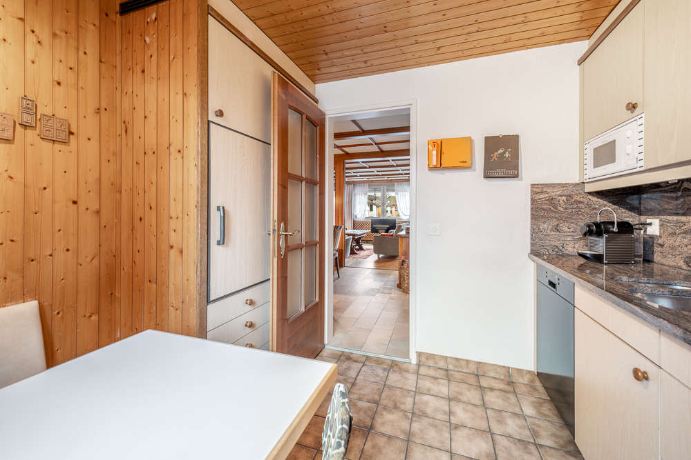 Kleine Küche mit Holzdecke und Durchgang zum Wohnbereich