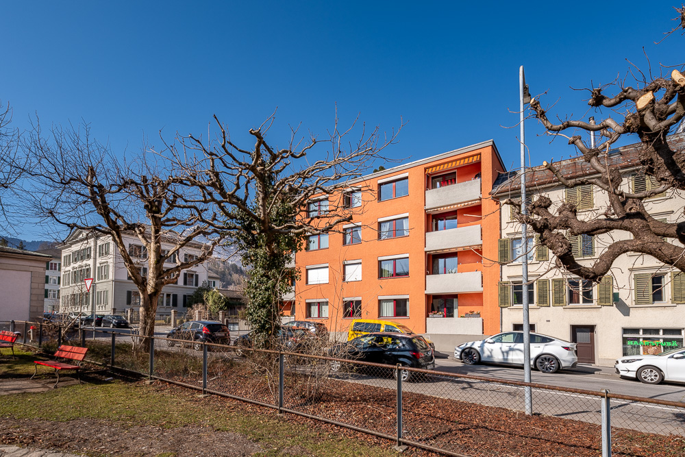 Straßenansicht eines Wohngebäudes mit Nachbarhäusern und Parkplätzen