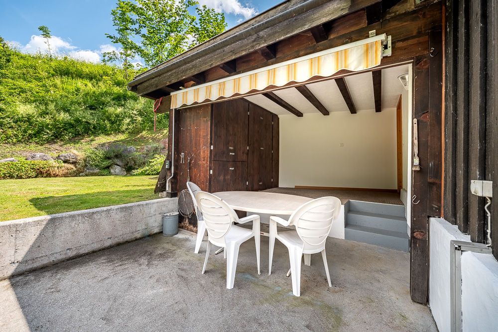 Überdachte Terrasse mit Sitzplatz und Holzschuppen