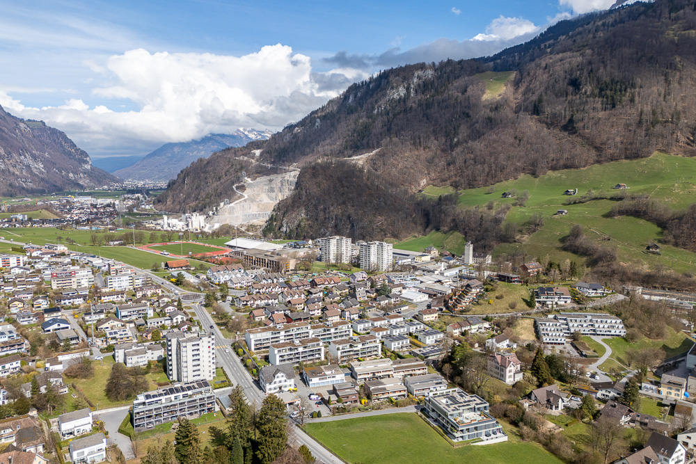 Luftaufnahme eines alpinen Tals mit Stadt und Bergen