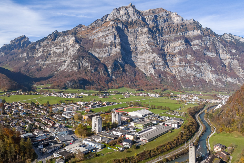 Luftaufnahme eines alpinen Tals mit Bergmassiv und Siedlung