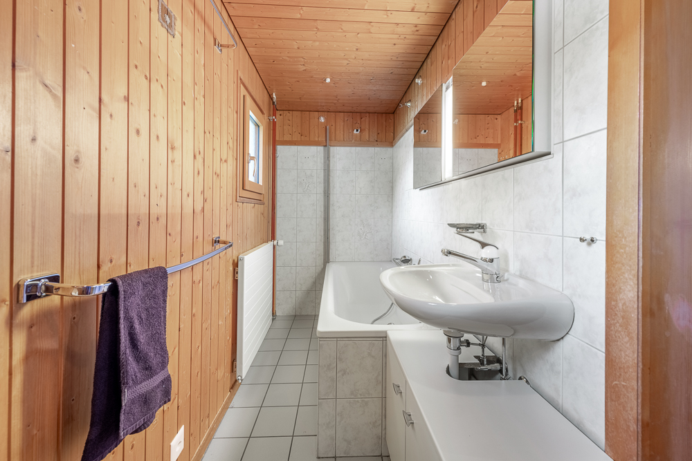 Badezimmer mit Holzvertäfelung und Badewanne