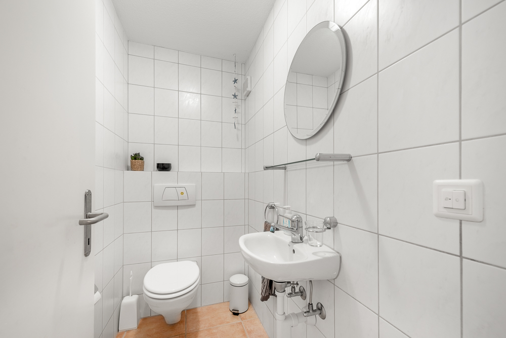 Gäste-WC mit weißer Wandfliese und Wand-WC