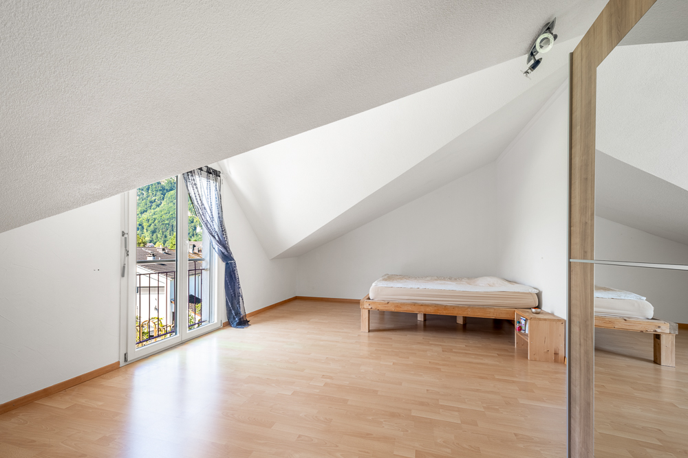 Dachzimmer mit Bett und Balkonfenster