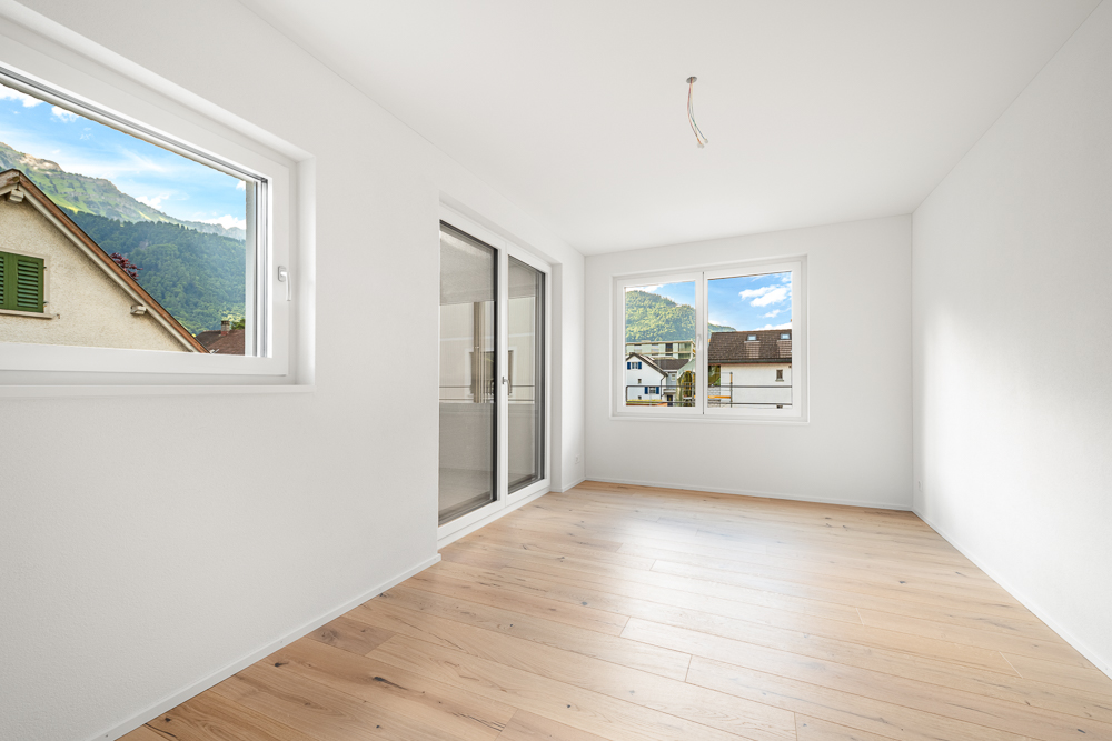 Leerer heller Raum mit zwei Fenstern und Balkon-/Terrassentür