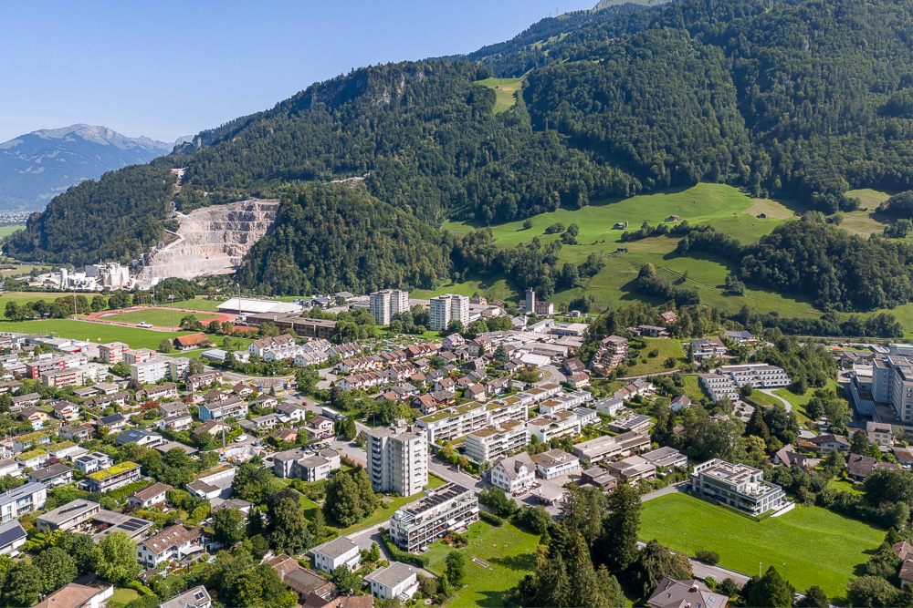 Luftaufnahme einer Alpenstadt mit Tal, Wohngebiet und Bergkulisse
