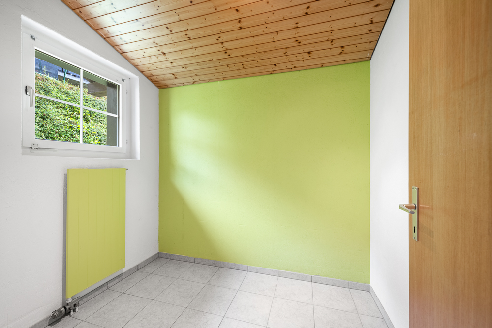 Heller kleiner Raum mit Holzdecke und grün akzentuierter Wand