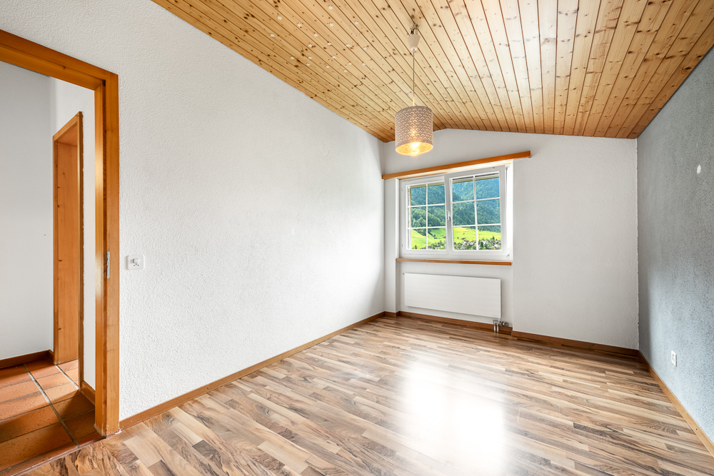 Helles leeres Zimmer mit Holzdecke und Blick ins Grüne