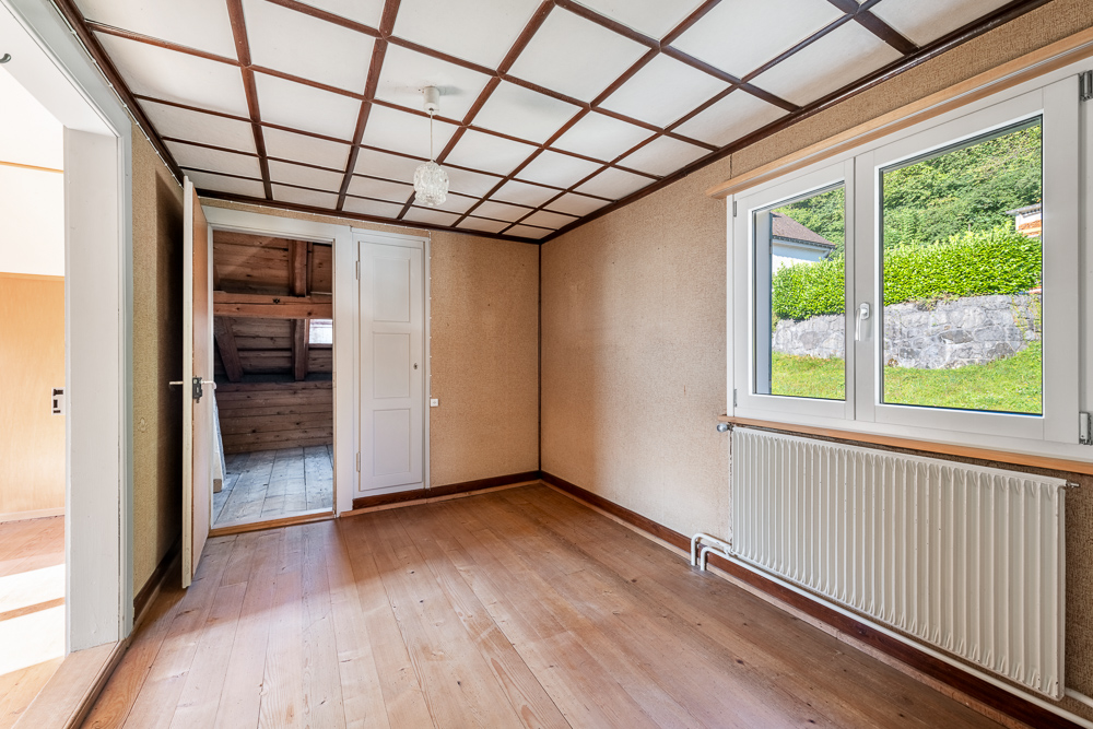 Leerer Raum mit Holzdecke, Fenster und Heizkörper