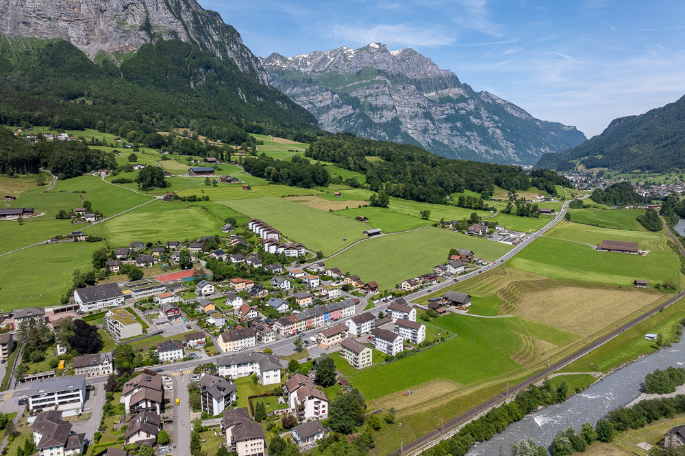 Luftaufnahme eines Alpentals mit Siedlung und Fluss