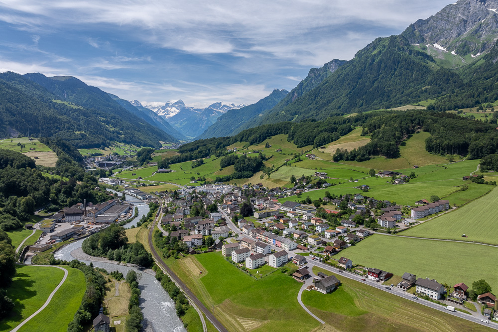 Luftaufnahme eines Alpentals mit Ortschaft und Fluss