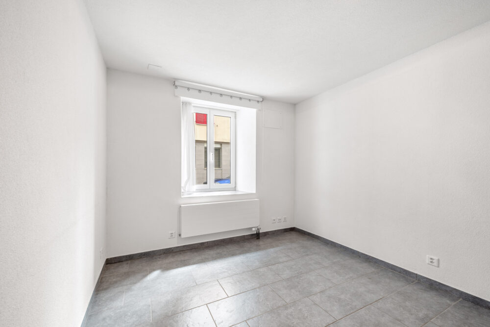 Leerer, heller Raum mit Fenster und Fliesenboden