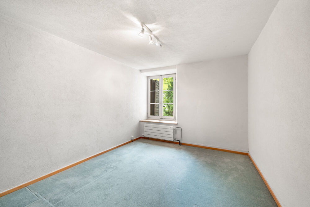Leerer, heller Raum mit Fenster und Heizkörper