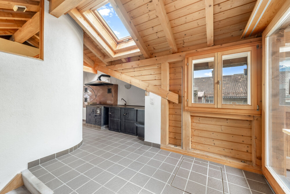 Gemütlicher Dachraum mit Holzverkleidung und kleinen Fenstern