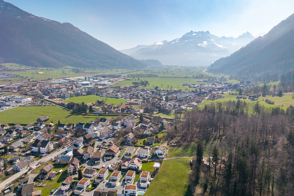 Luftaufnahme eines Tals mit Ortschaft und Bergen