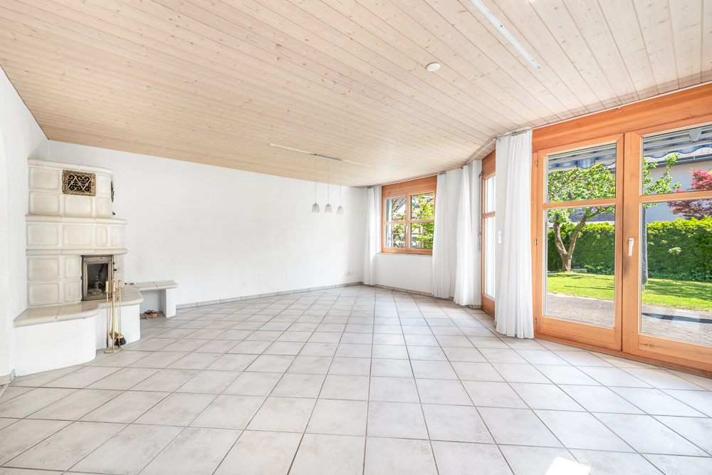 Heller Wohnraum mit Kachelofen und Gartenzugang