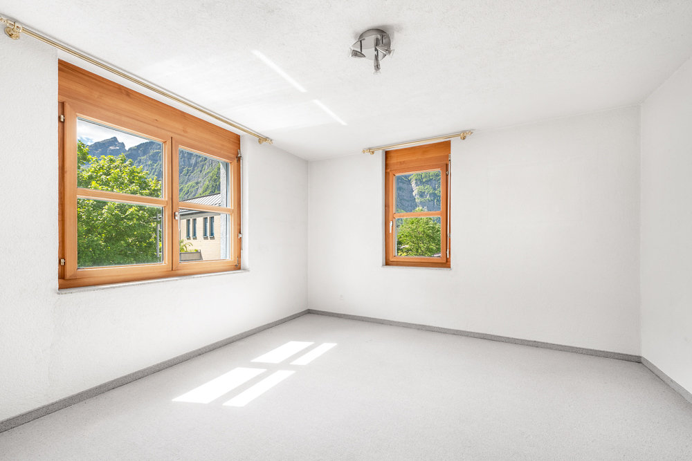 Heller leerer Raum mit Holzfenstern und Bergblick