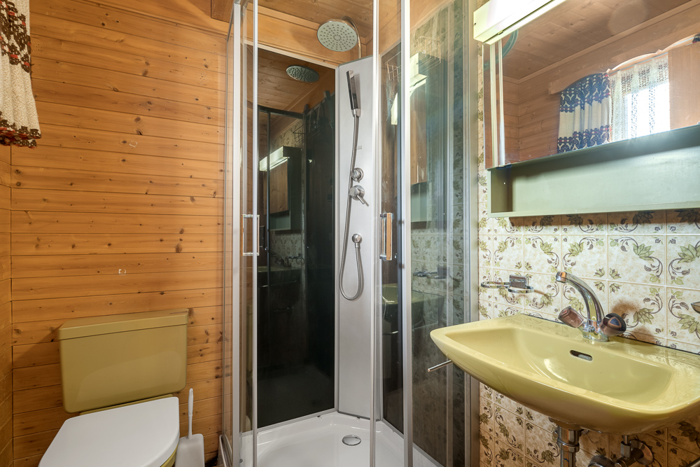Kleines Badezimmer mit Holzverkleidung und Duschkabine