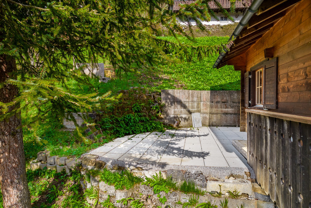 Holzhaus mit gepflasterter Terrasse und Gartenhang