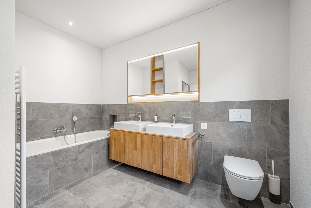 Modernes Badezimmer mit Wanne, Doppelwaschtisch und wandhängendem WC