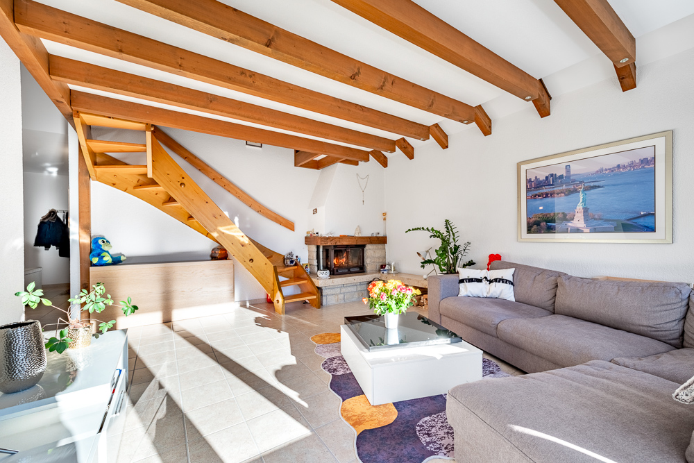 Gemütliches Wohnzimmer mit sichtbarer Holztreppe und Kamin