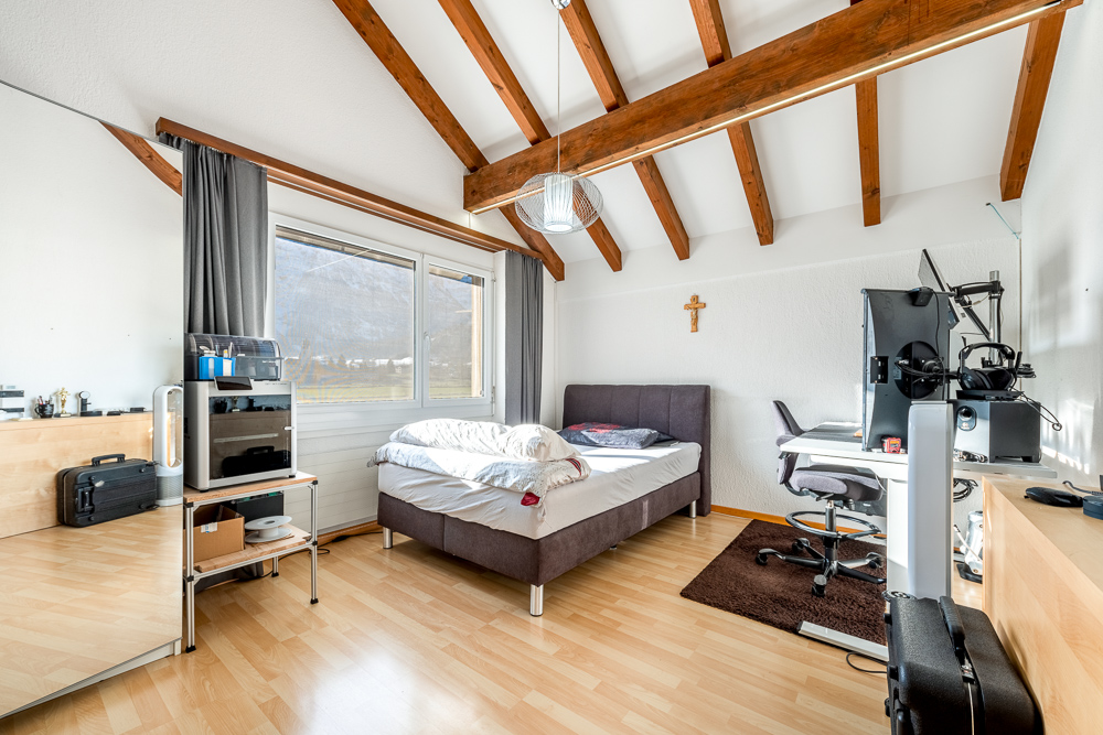 Hell eingerichtetes Schlafzimmer mit Arbeitsbereich