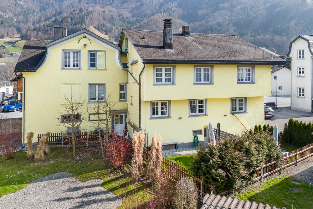 Gelbes Wohnhaus mit Garten und Bergkulisse