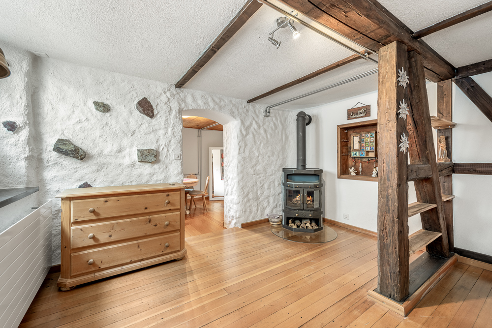 Gemütlicher Raum mit Holzofen und sichtbaren Holzbalken
