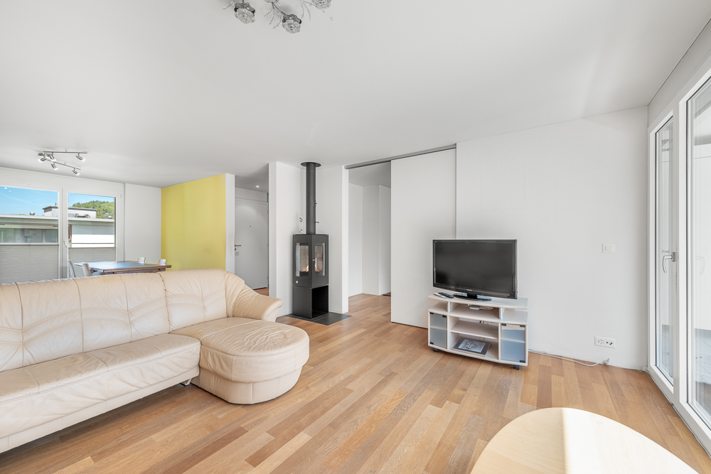 Heller Wohnraum mit Kamin und Balkonzugang