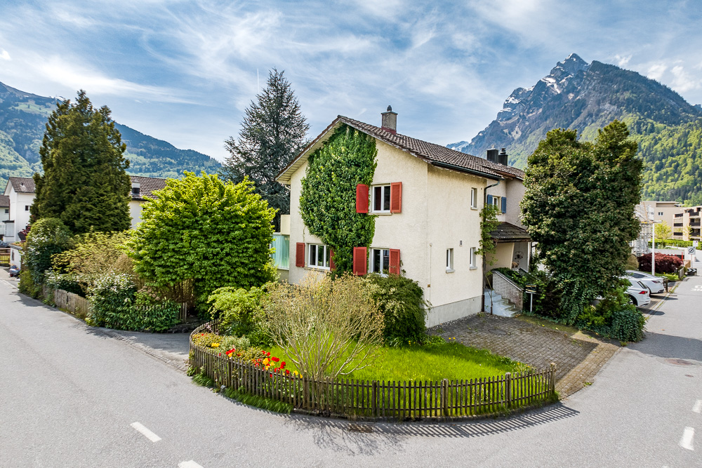 Wohnhaus an einer Straßenkreuzung mit Bergkulisse