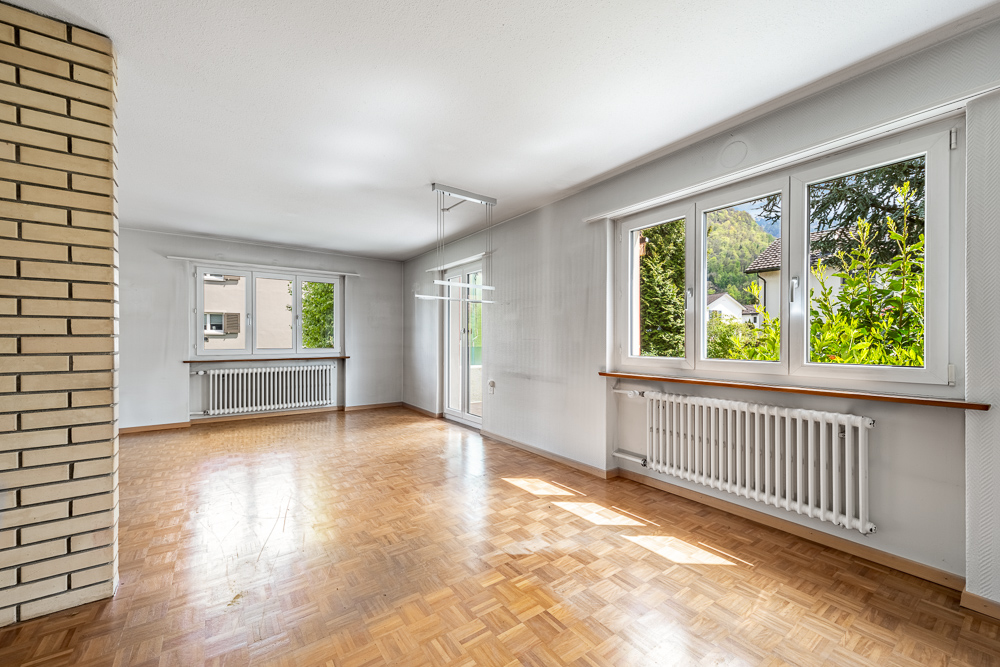 Heller Wohnraum mit Parkett und großen Fenstern