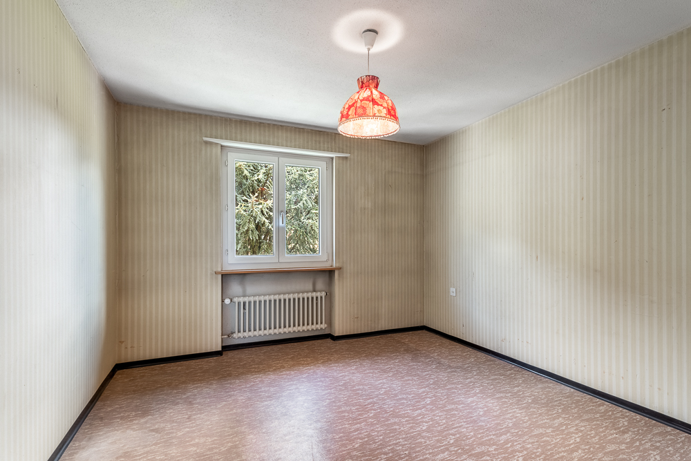 Leerer, einfach gestalteter Raum mit Fenster und Heizkörper