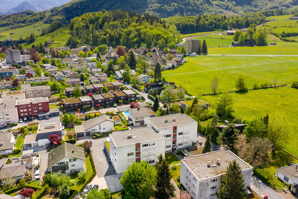 Luftaufnahme eines Wohngebiets in grüner Tallandschaft