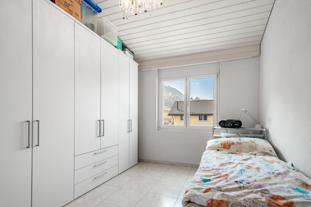 Kleines Schlafzimmer mit Einbauschrank und Fensterblick