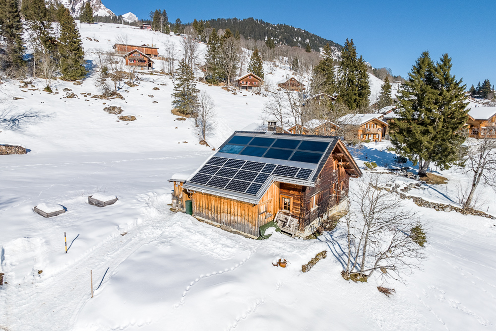 Alpines Holzhaus mit Solardach im Schnee