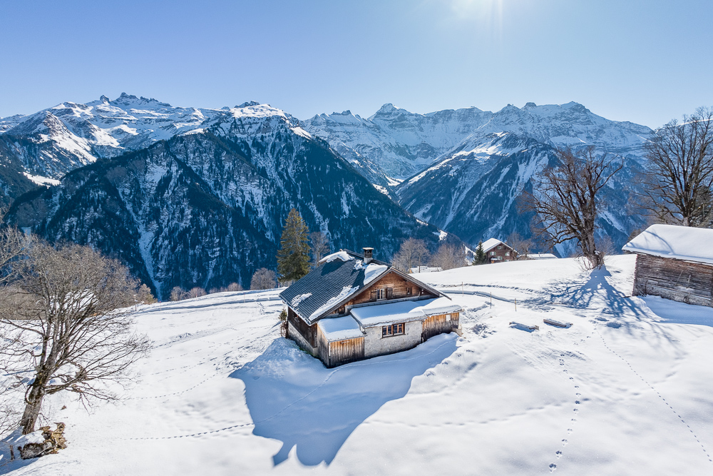 Verschneite Berghütte mit Alpenpanorama