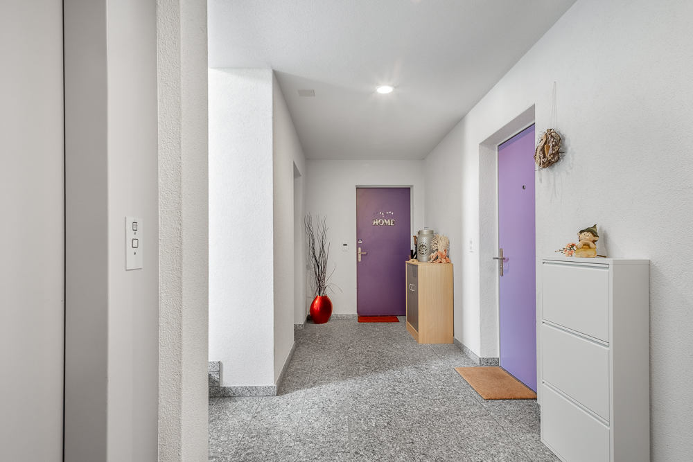 Heller Eingangsflur mit violetten Türen