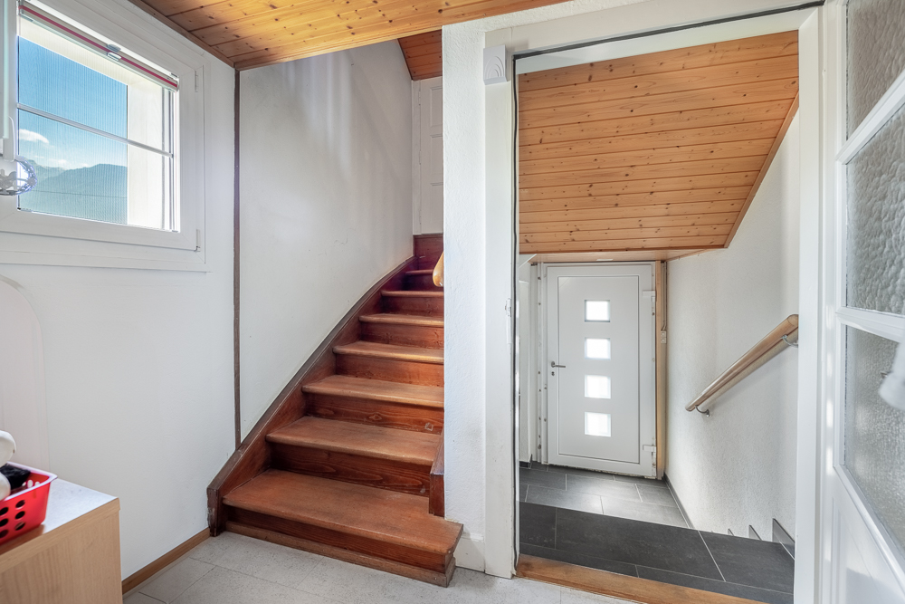 Heller Treppenhaus-Flur mit Holztreppe und Eingangstür