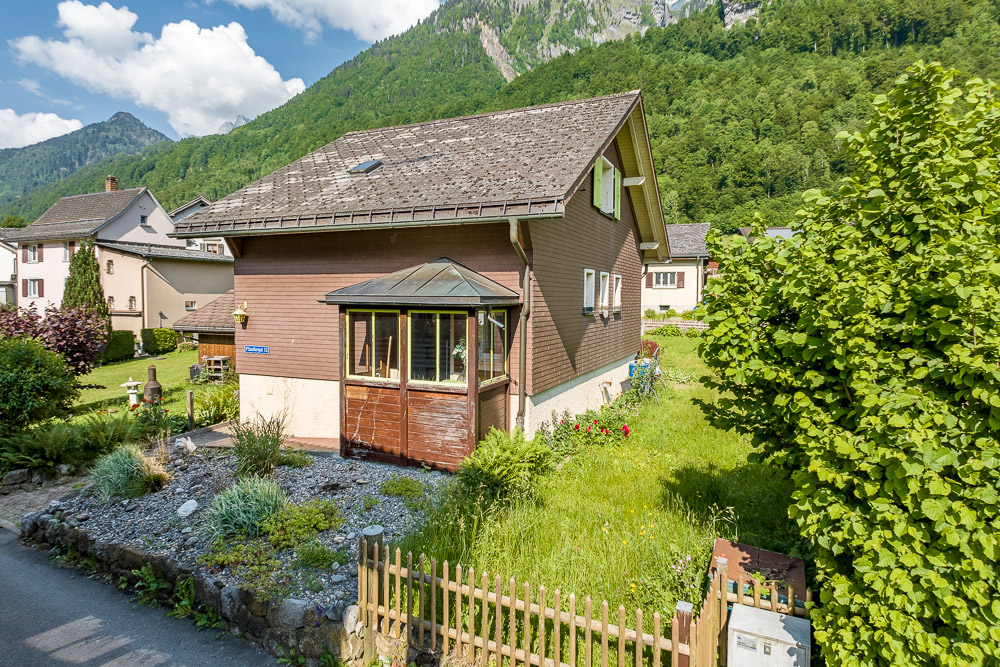 Haus mit Garten vor Alpenkulisse