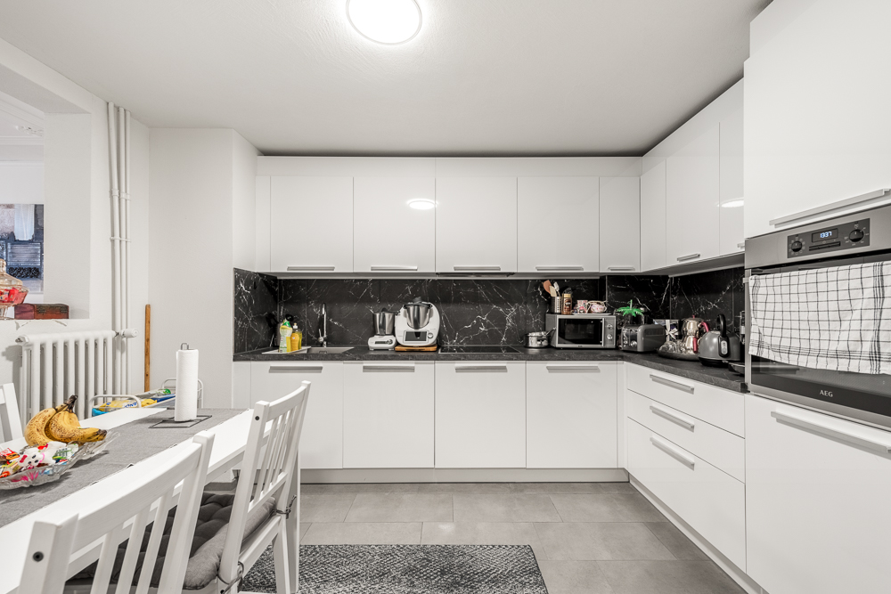 Moderne weiße Küche mit Essbereich