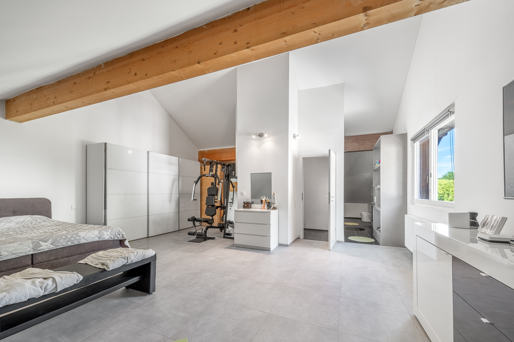 Helles Schlafzimmer mit Dachbalken und integriertem Fitnessbereich