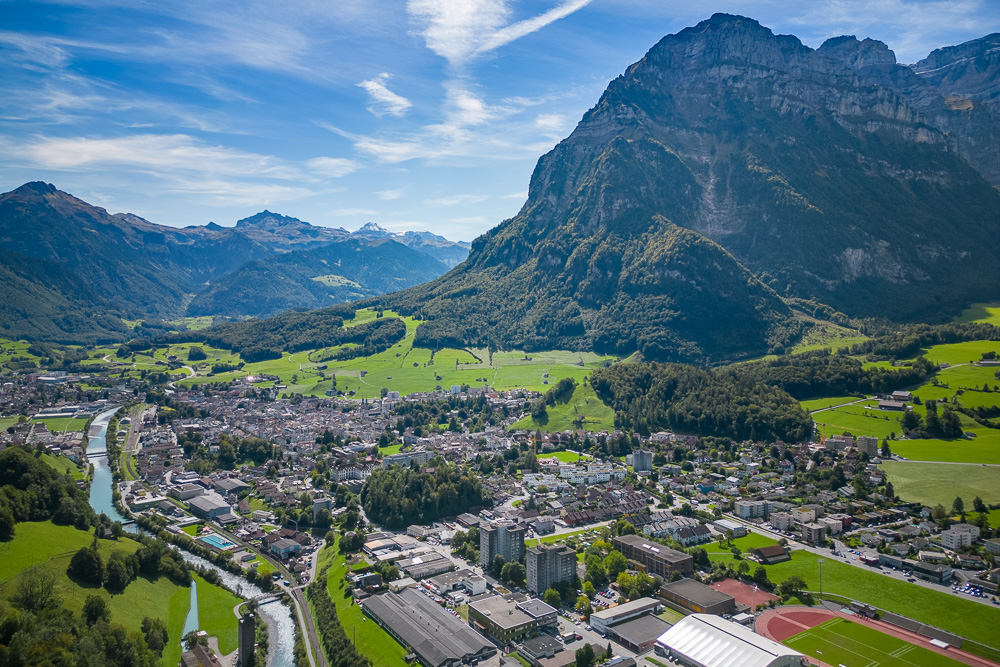 Luftaufnahme einer alpinen Stadt mit Tal und Bergen